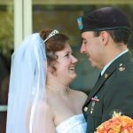 Angie and Peter smiling at each other on their wedding day, with Peter in his Army dress uniform and Angie wearing her wedding gown and veil