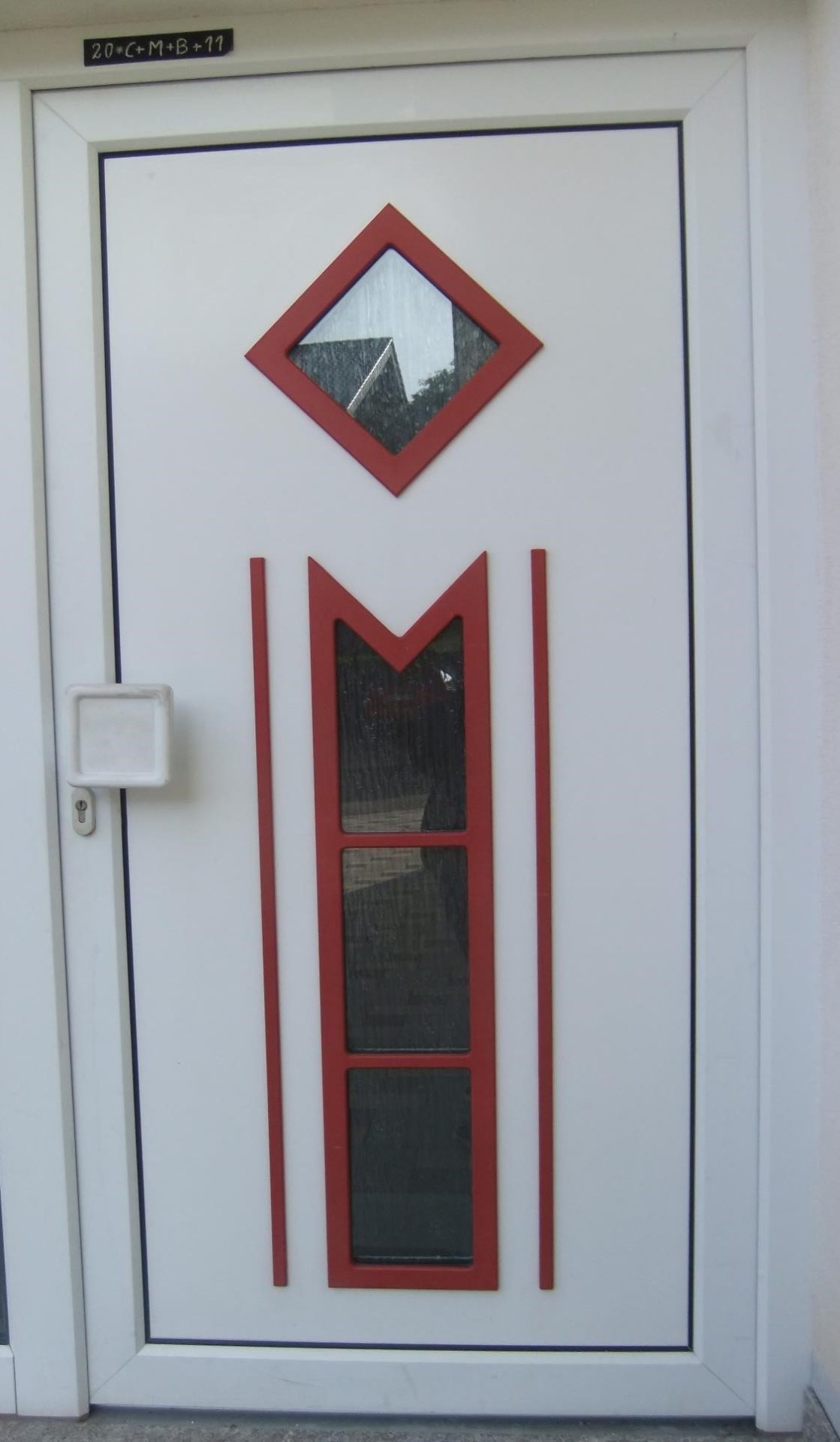 Weathered wooden door in Germany, with red trim, small windows, and an inscription above the doorway.