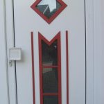 Weathered wooden door in Germany, with red trim, small windows, and an inscription above the doorway.