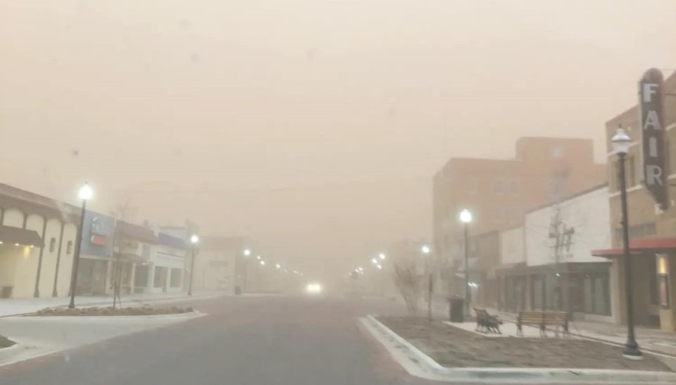 A nearly empty downtown street with low visibility during a West Texas dust storm.