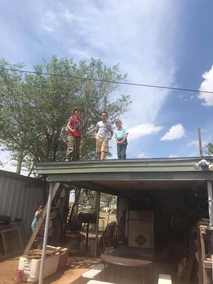 Three children standing on the roof of the carport at the Country House