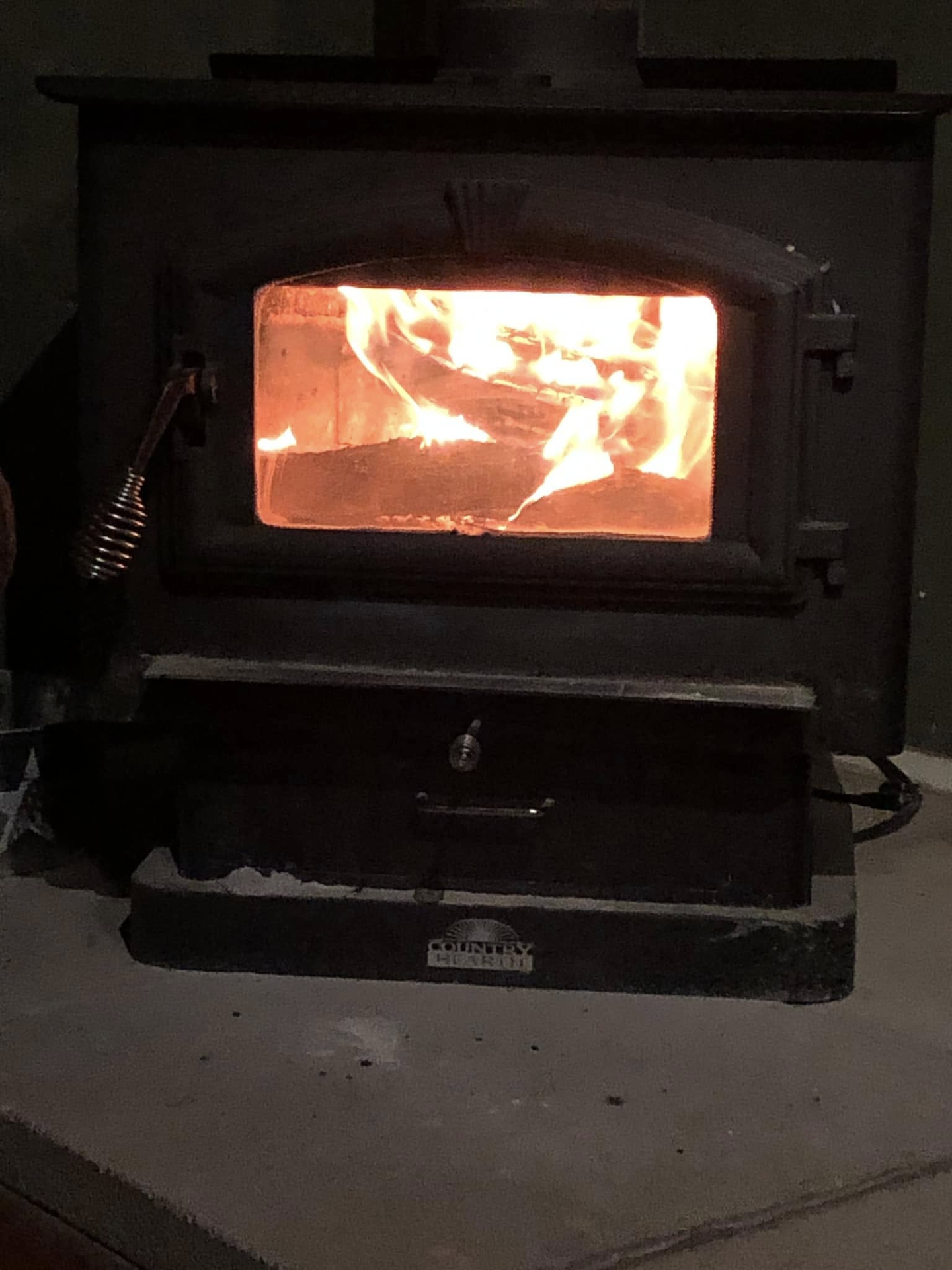Flames burn around logs inside a wood-burning stove.