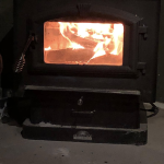 Flames burn around logs inside a wood-burning stove.