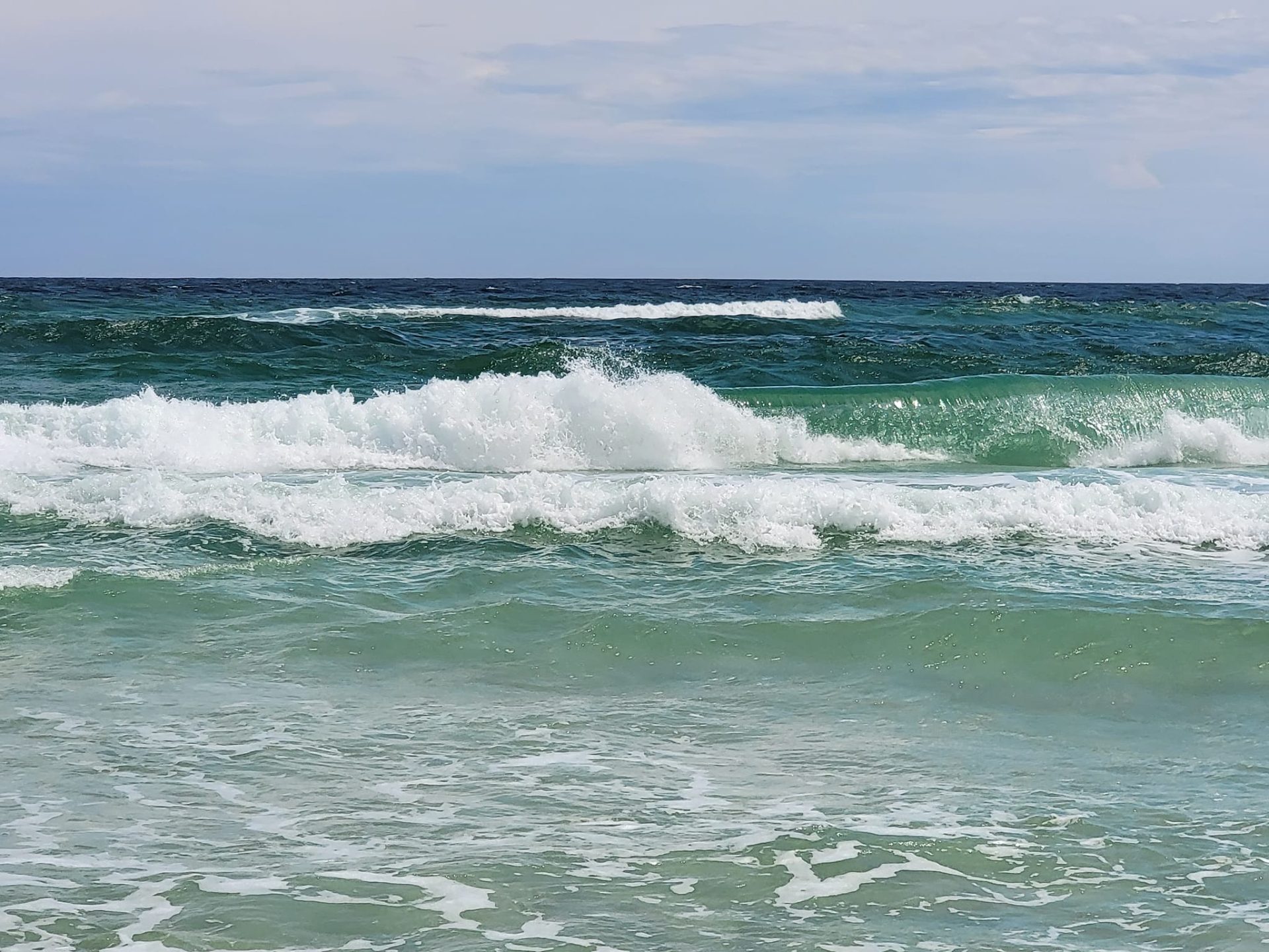 Ocean waves of varying sizes rolling and breaking toward the shore, illustrating the changing waves of grief.