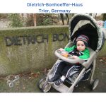Young Dietrich sits in his stroller beside the Dietrich Bonhoeffer House sign in Trier, Germany.