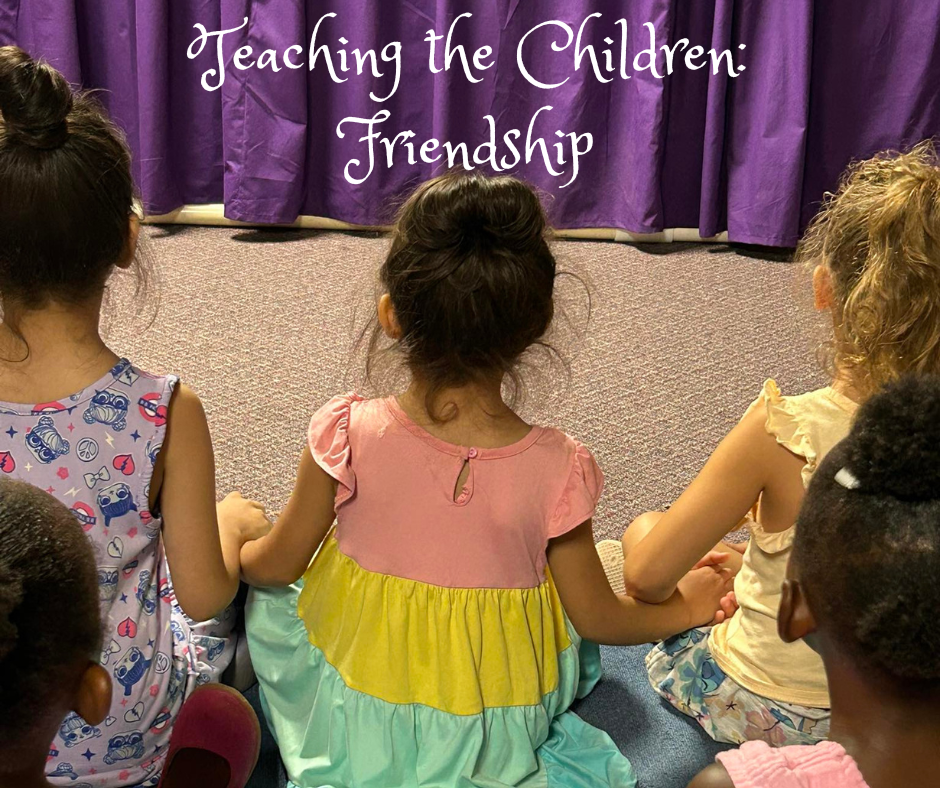 Young children sit together holding hands during a Bible class puppet show.