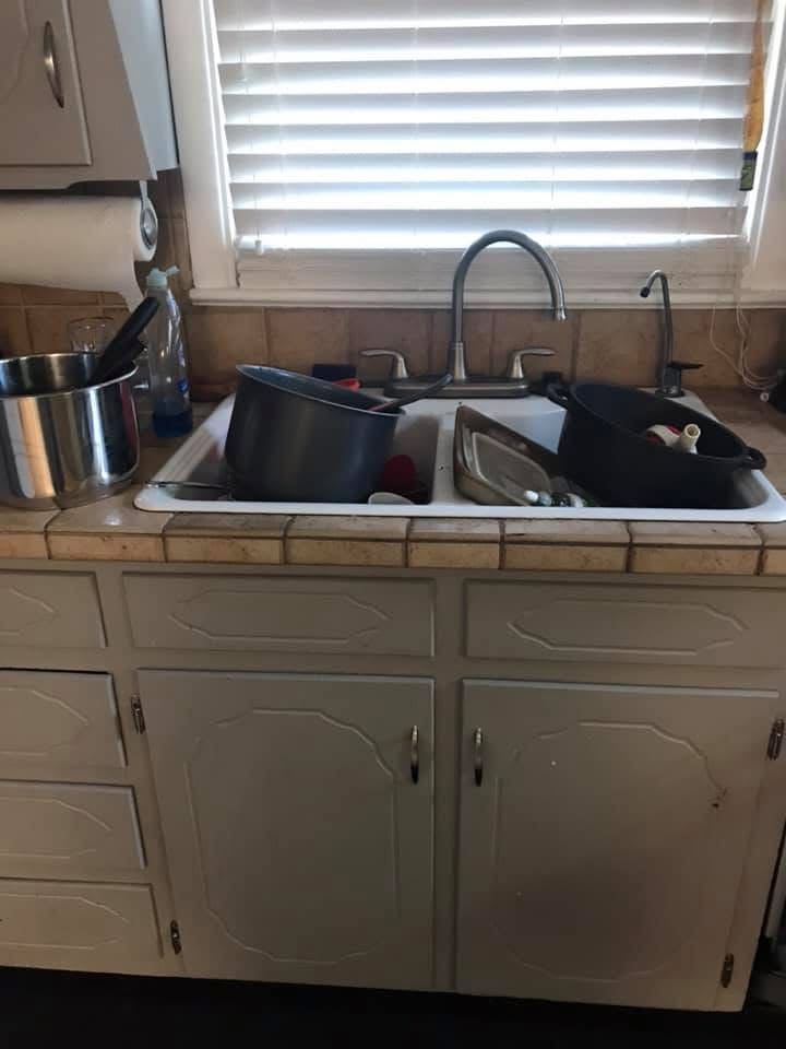 Kitchen sink filled with dirty pots, pans, and dishes waiting to be washed.